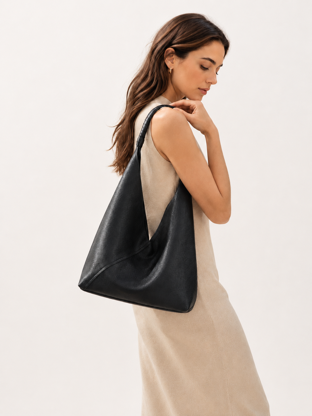 #Black top-grain leather hobo shoulder bag worn by woman in minimalist neutral setting