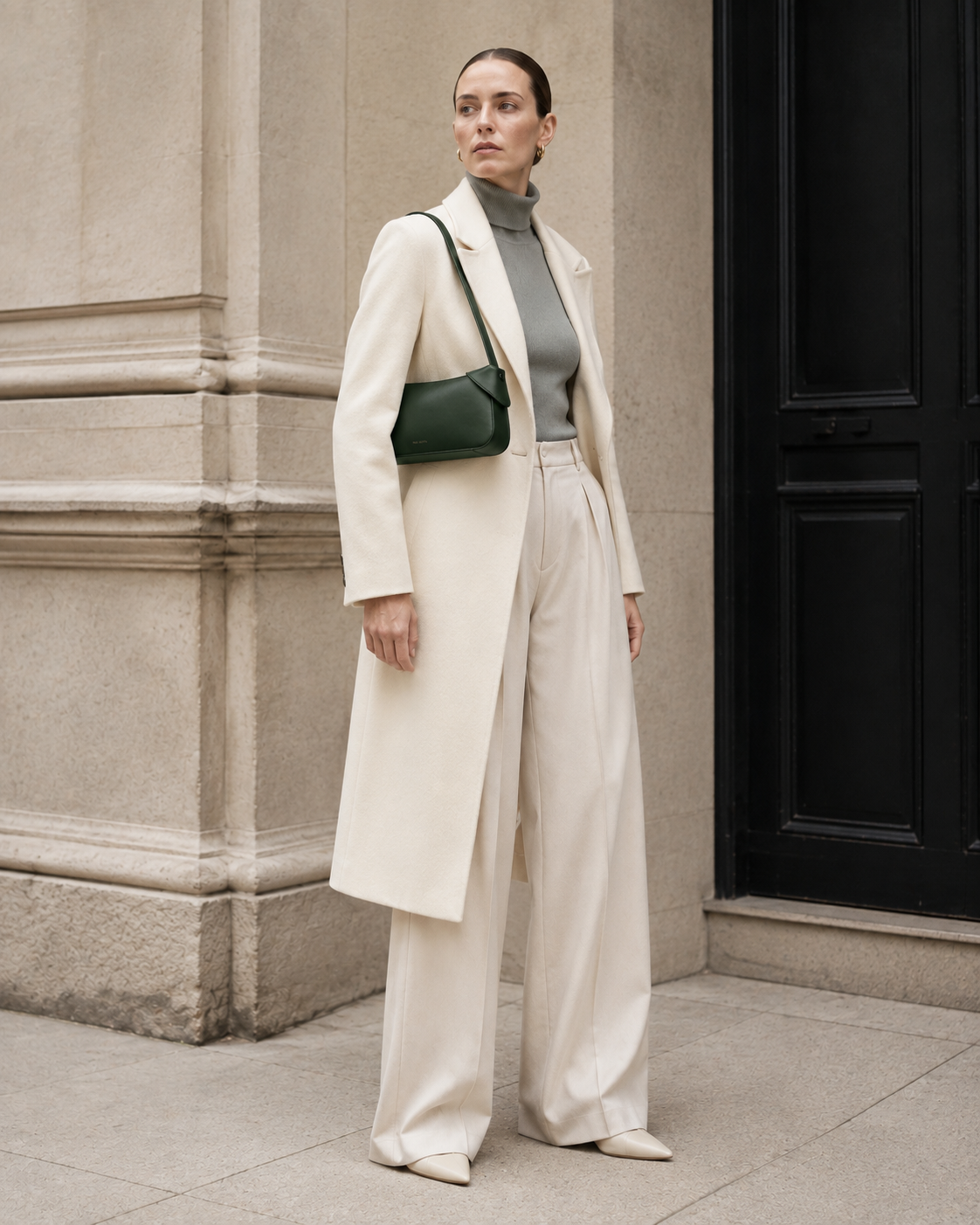 Woman in tailored neutrals carries the deep green MUYLOTTA ML-SH05 shoulder bag on her shoulder by a limestone wall.