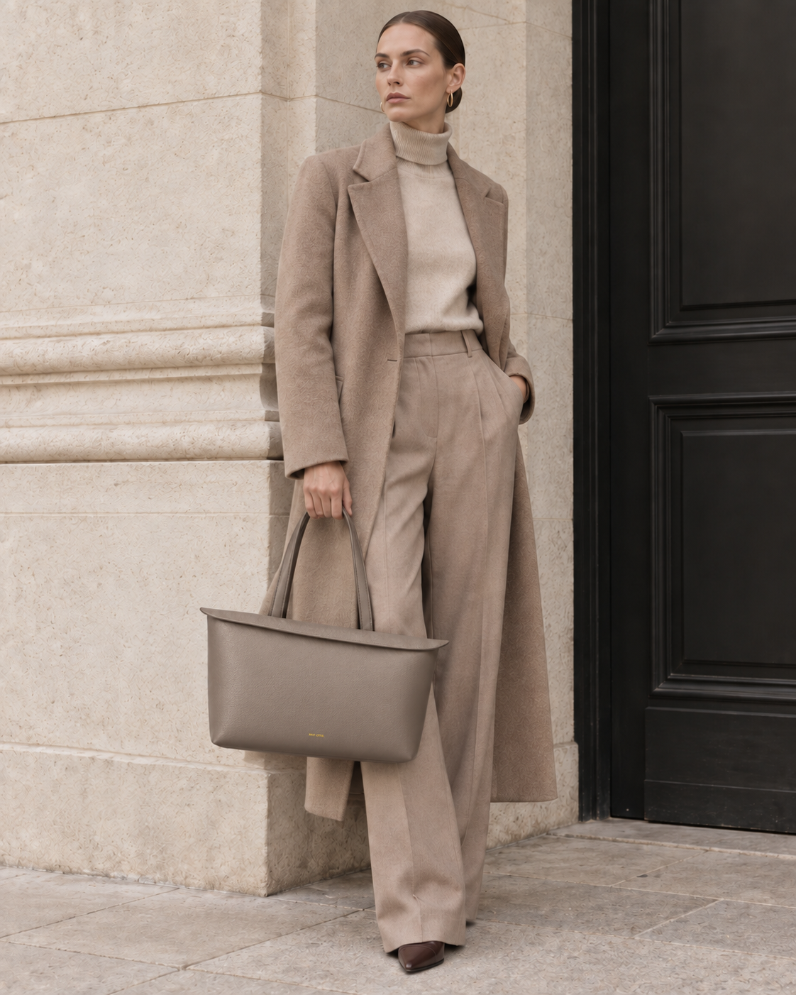 Model carrying the MUY LOTTA Floating Eave Span Limestone Taupe leather tote.